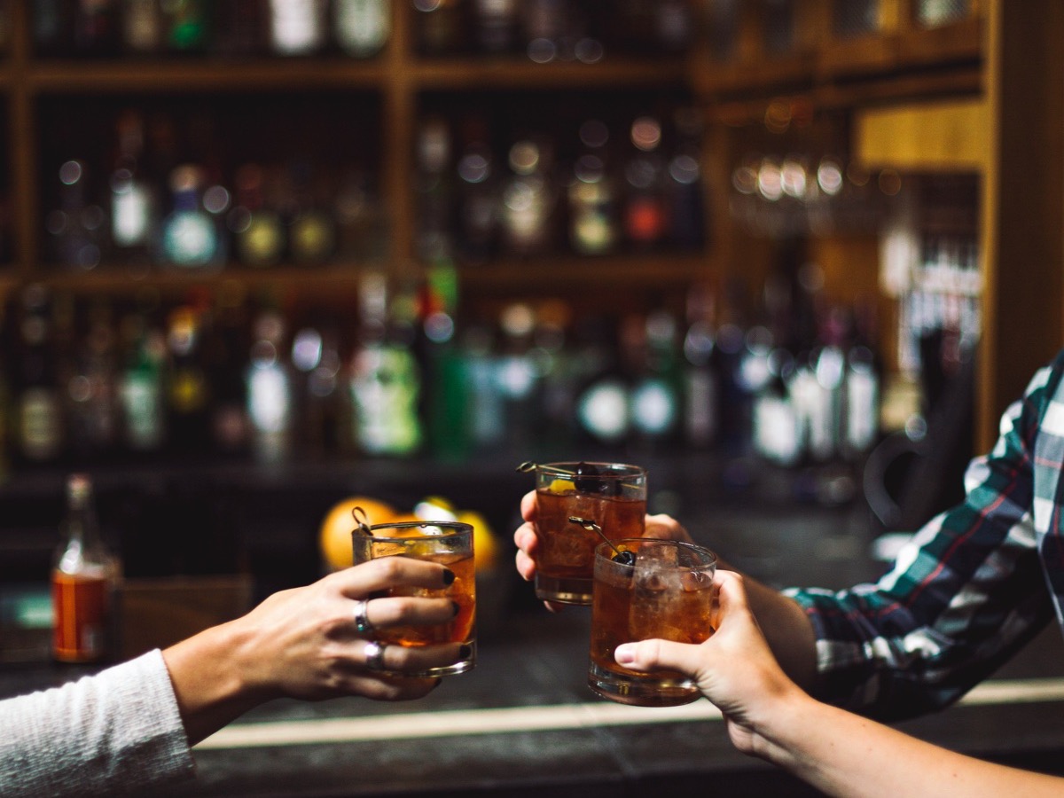 Three glasses meeting over a bar
